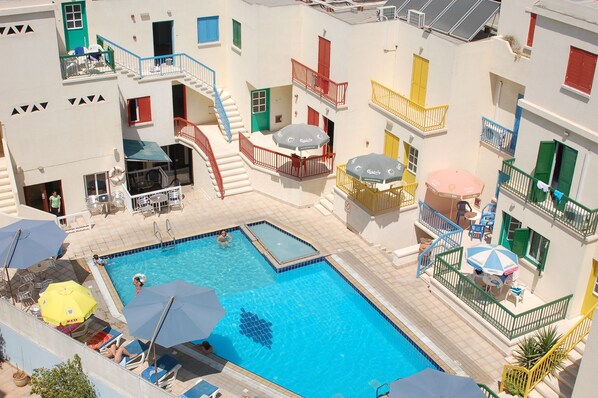 Una piscina al aire libre, sombrillas, sillones reclinables de piscina