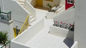 Un edificio blanco con varios balcones y un patio central con una puerta amarilla.