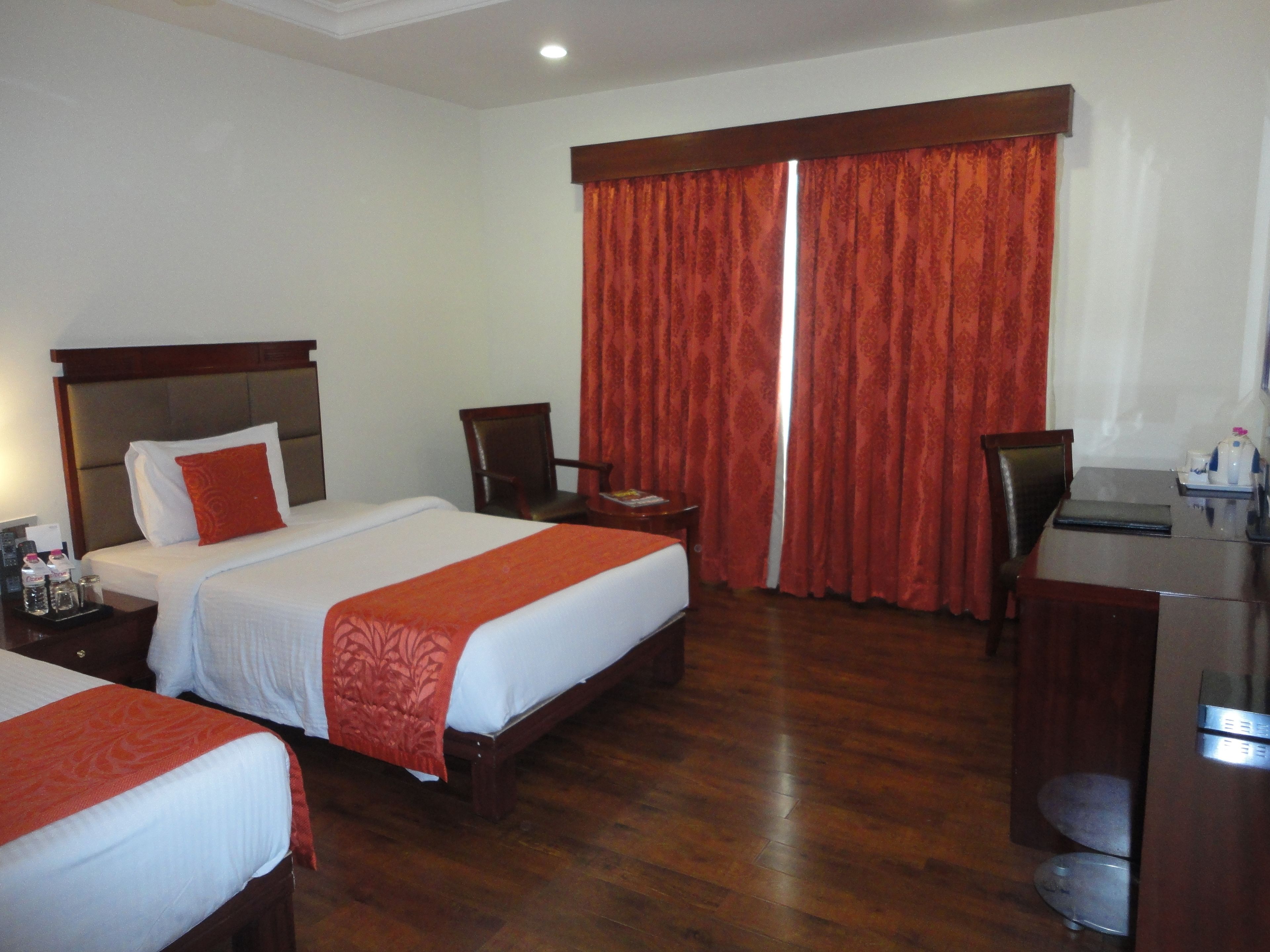 A hotel room with two beds, a desk, and a chair.
