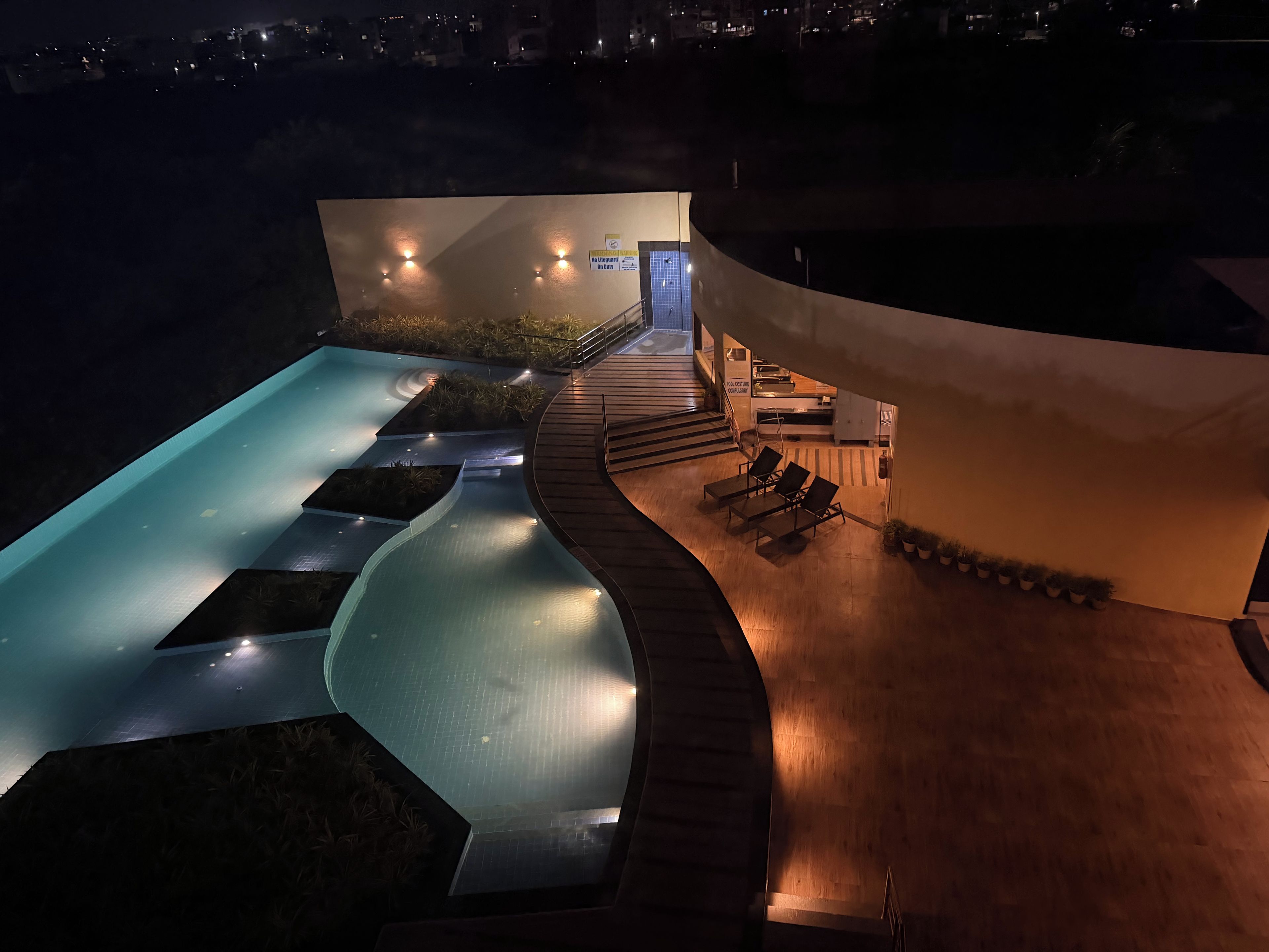 A swimming pool with a curved design, a wooden deck, and a poolside area with lounge chairs.