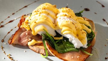 Un plato con un desayuno, posiblemente huevos Benedict, salsa y decoración.