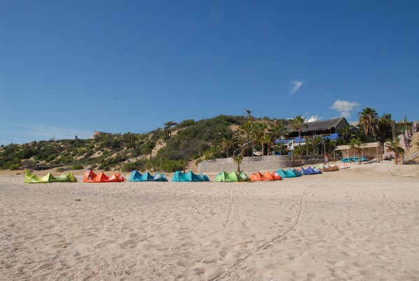 Una playa con carpas coloridas y un edificio con techo de paja.