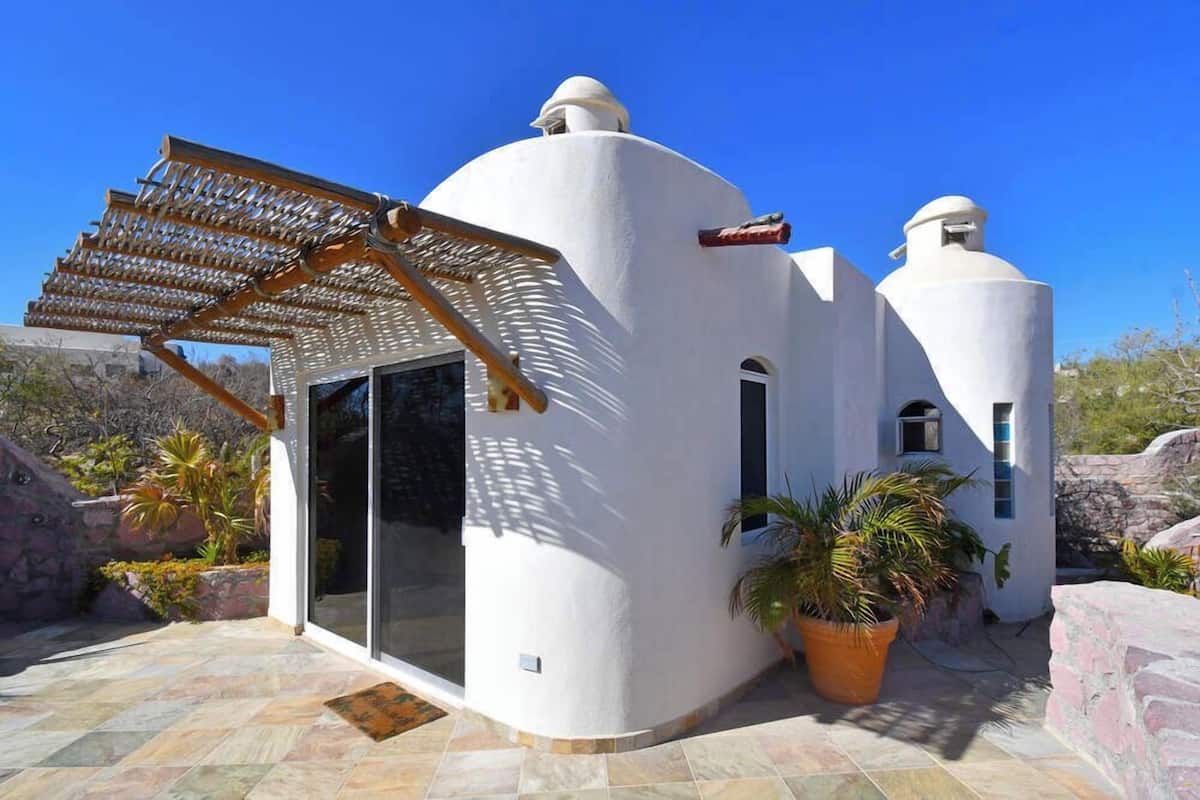 A modern building with a white exterior, a glass door entrance, and a pergola structure.