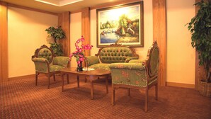 A room with four green upholstered chairs, a wooden coffee table, and a painting of a bridge over water on the wall. - Hotel Regal Malaysia (George Town)