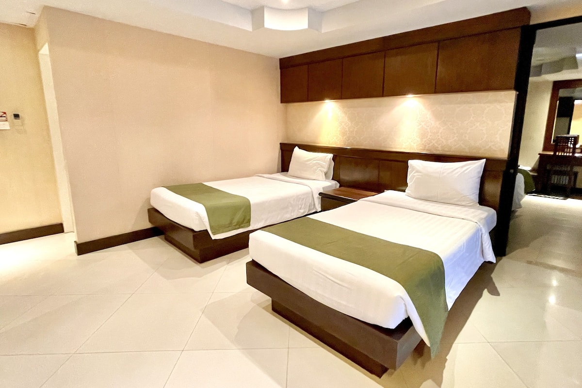 A hotel room with two beds, a wooden headboard, and a tiled floor.