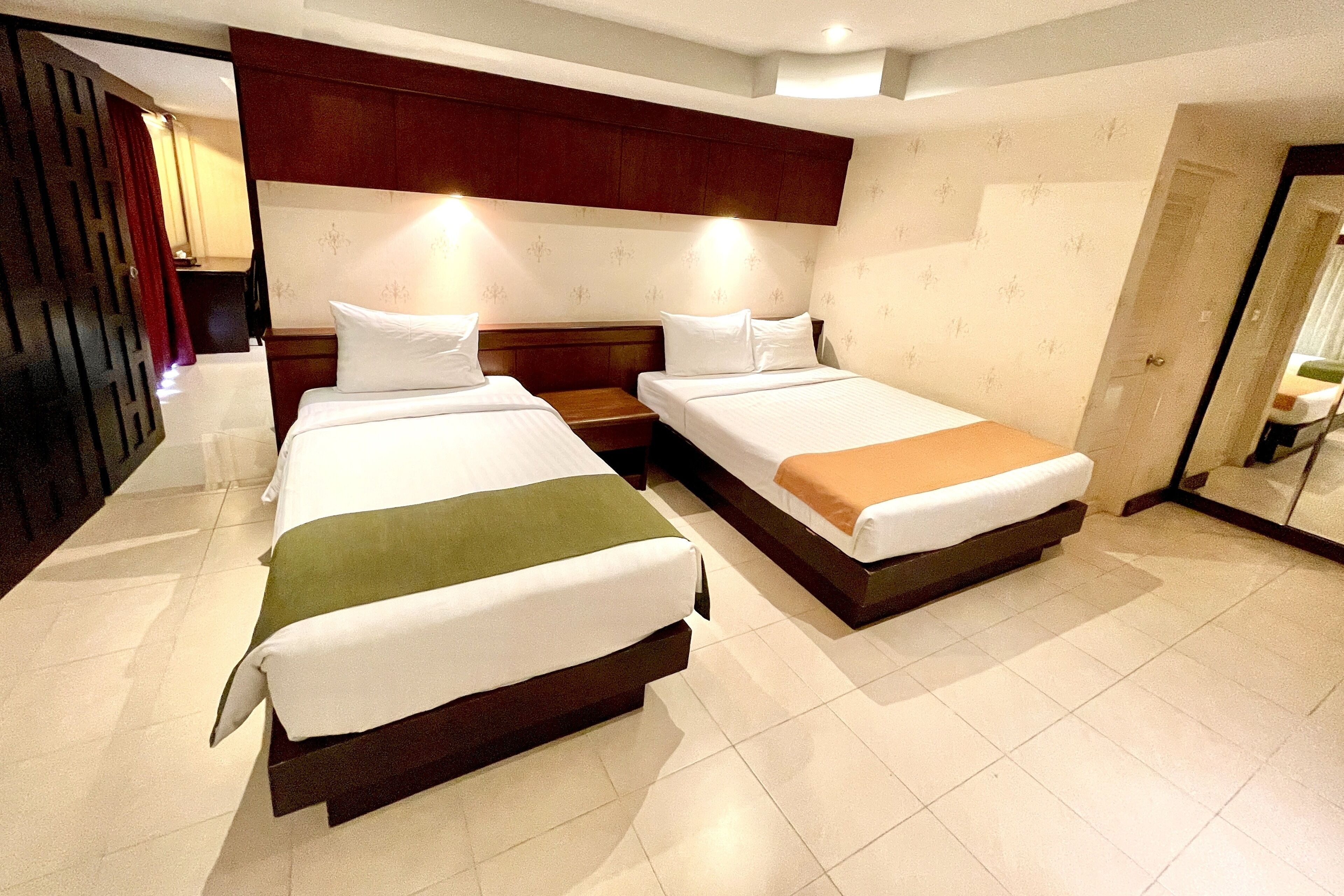 A hotel room with two beds, a wooden headboard, and a large mirror.