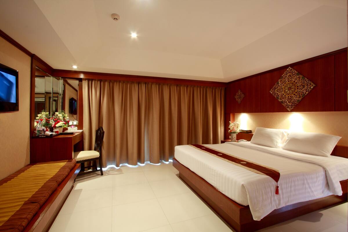 A hotel room with a large bed, a desk with a computer, a chair, and a TV.