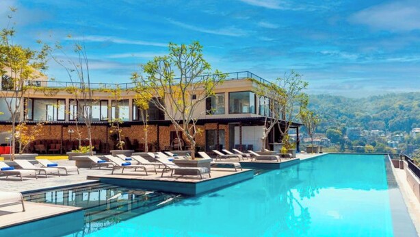 A modern hotel with a rooftop infinity pool, lounge chairs, and a view of the surrounding landscape. - Thilanka Hotel (Kandy)