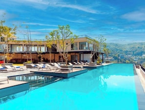 A modern hotel with a rooftop infinity pool, lounge chairs, and a view of the surrounding landscape. - Thilanka Hotel (Kandy)