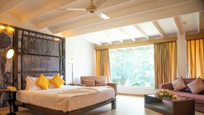 A modern hotel room with a bed, a sofa, a coffee table, and a large window with curtains. - Thilanka Hotel (Kandy)