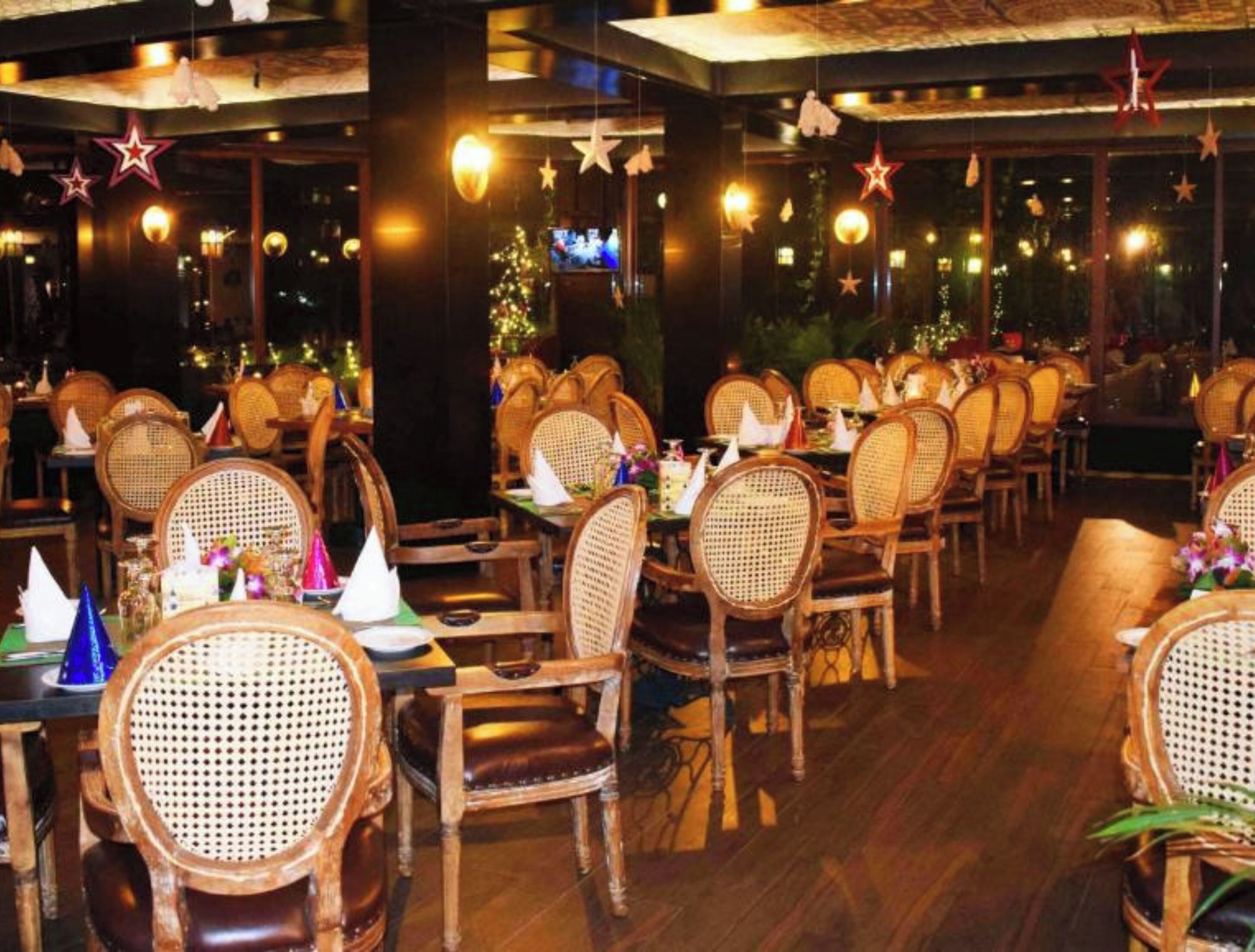 A restaurant with wooden chairs and tables, decorated with star-shaped lights.