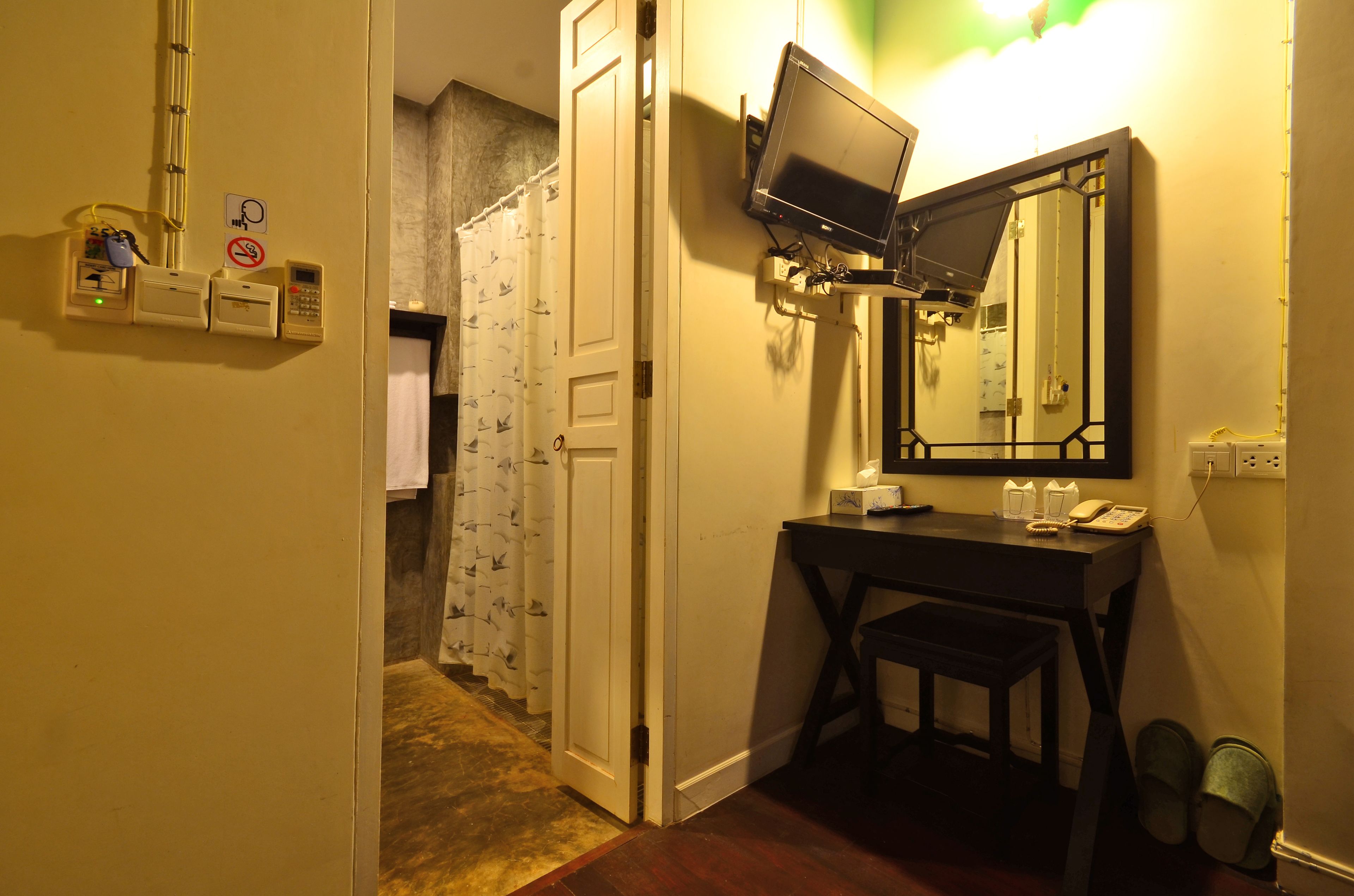 Een hotelkamer met een bureau, stoel, televisie en een spiegel.