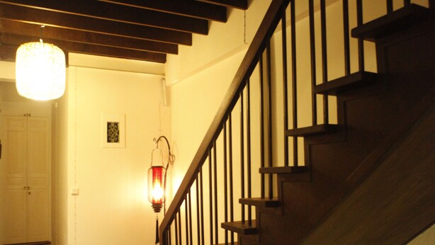 Un escalier avec des marches en bois et des rampes noires, menant à une porte dotée d’un cadre blanc.