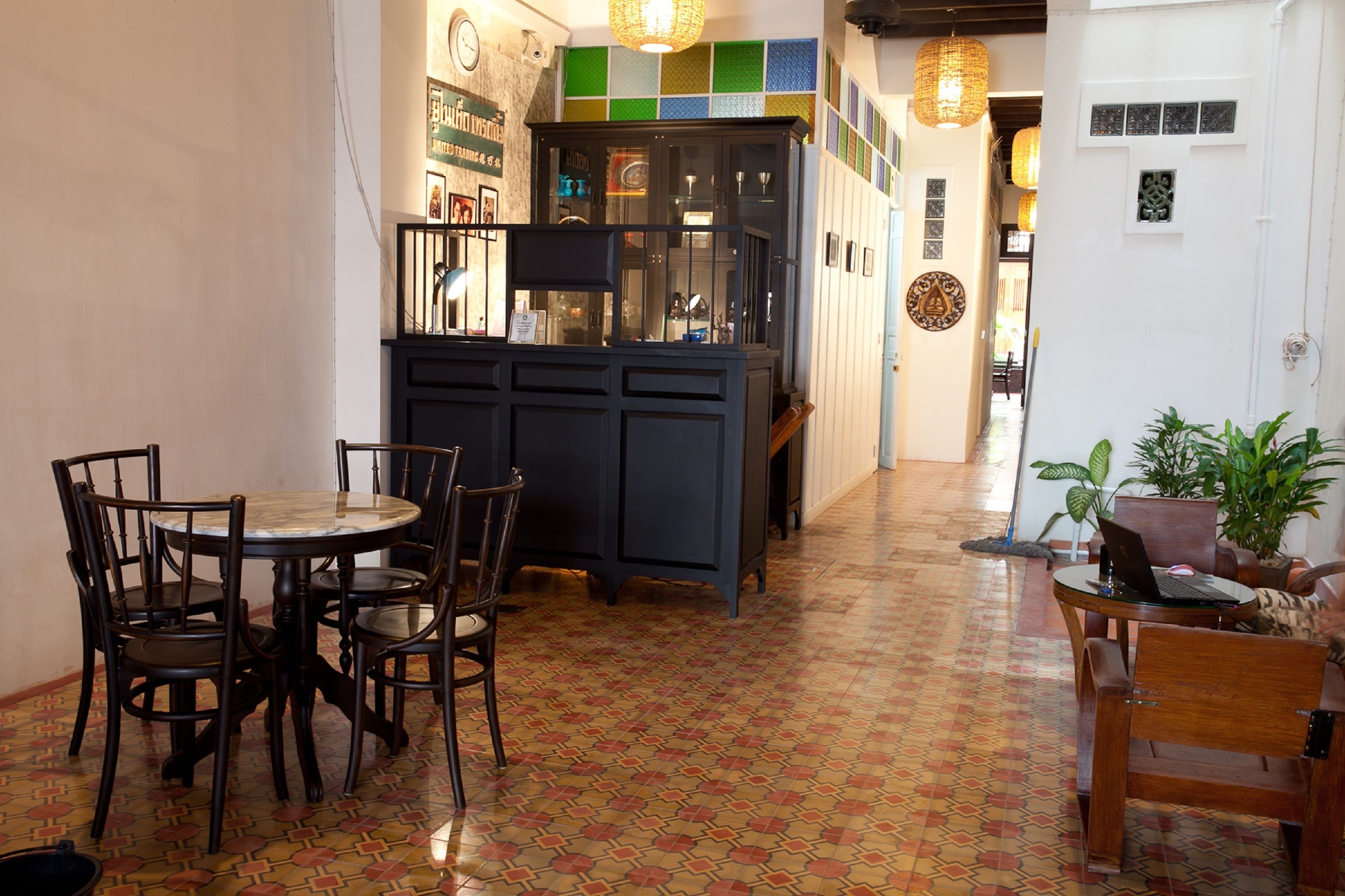 A dining area with a round table and chairs, a dark wooden cabinet, and a patterned floor.