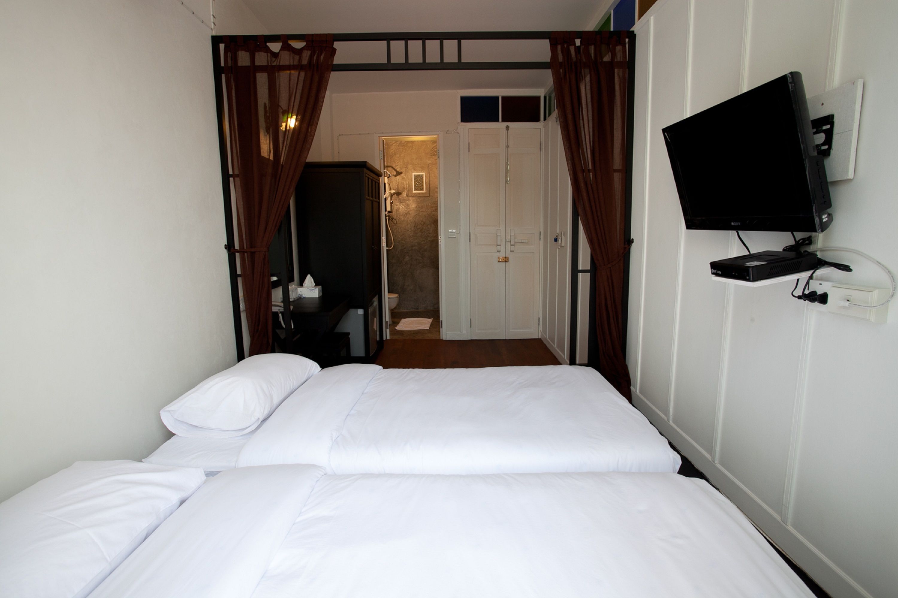 A hotel room with a bed, a television mounted on the wall, and a door leading to a bathroom.