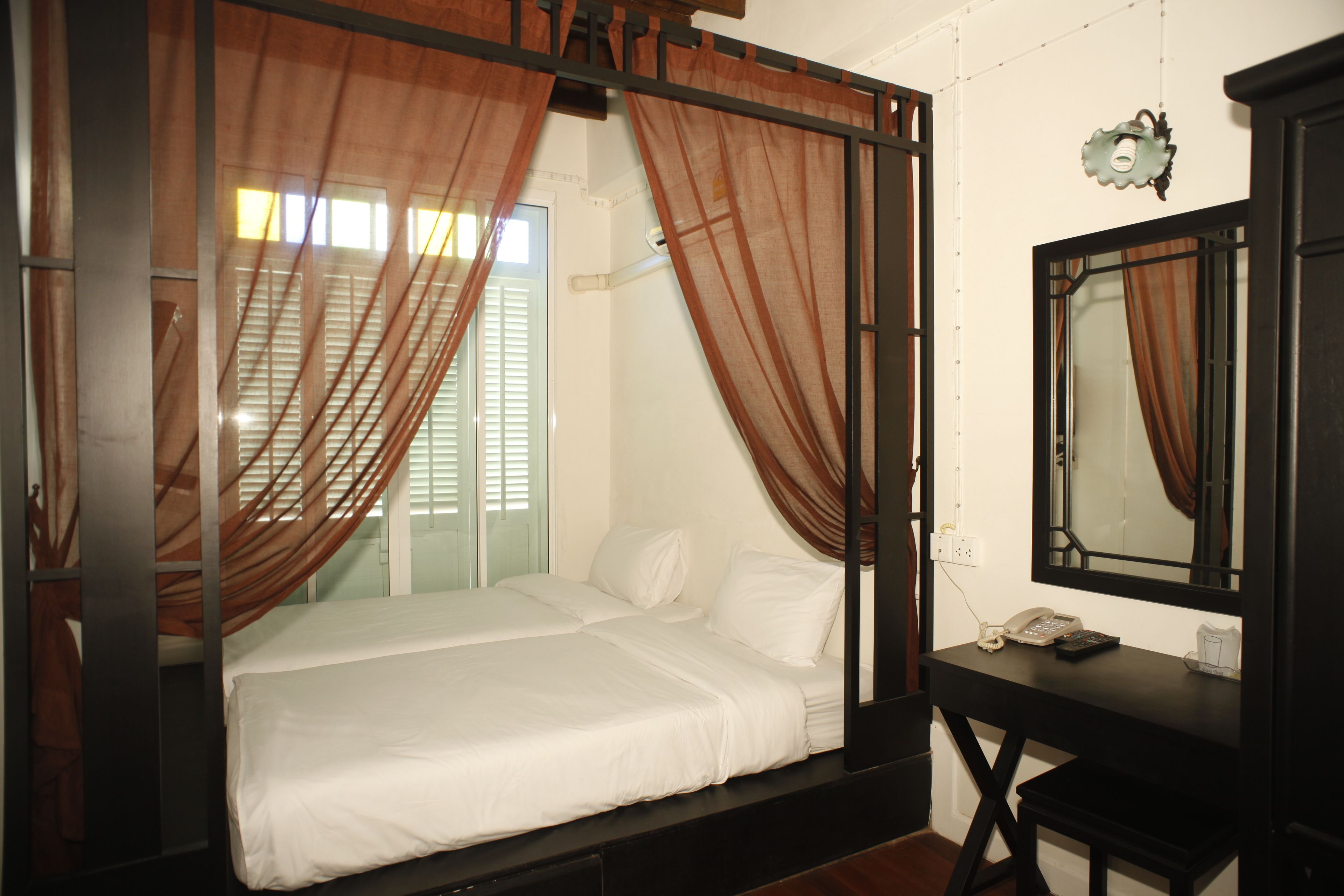 Une chambre à coucher avec un lit, des rideaux, un bureau et un miroir.