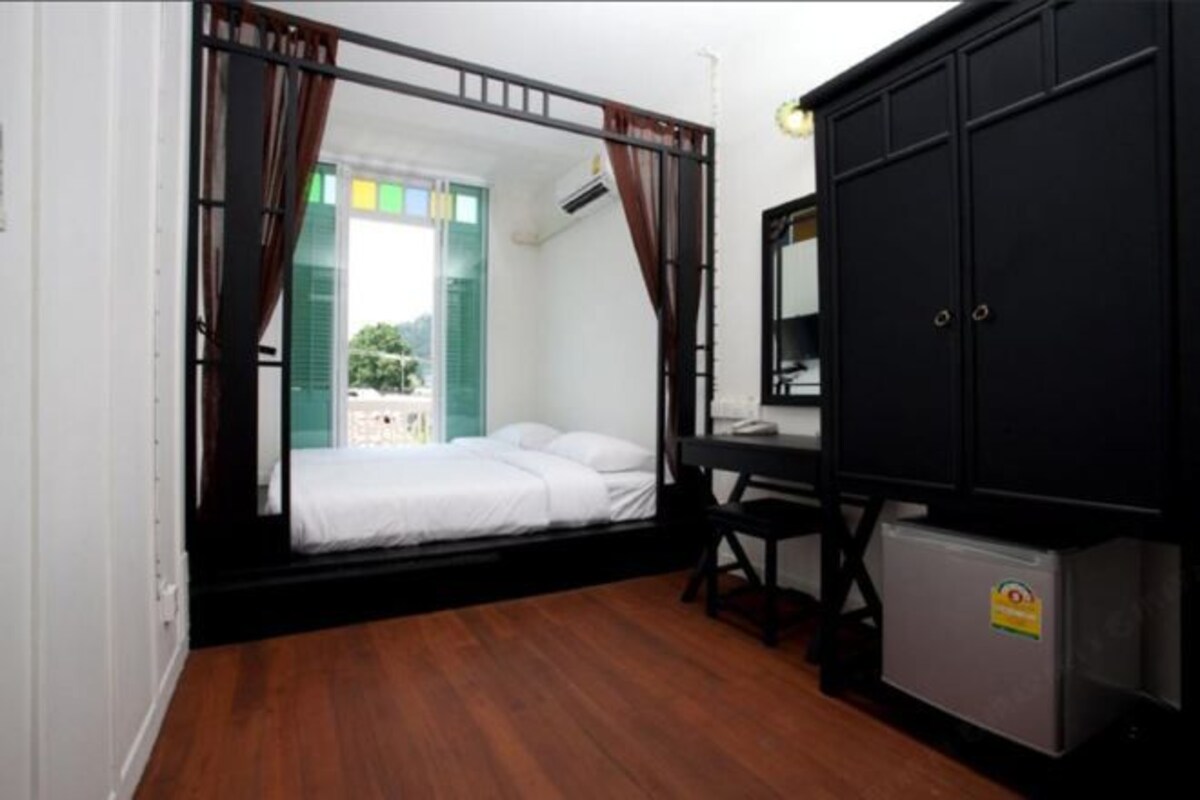 Una habitación con cama, escritorio y un refrigerador pequeño.