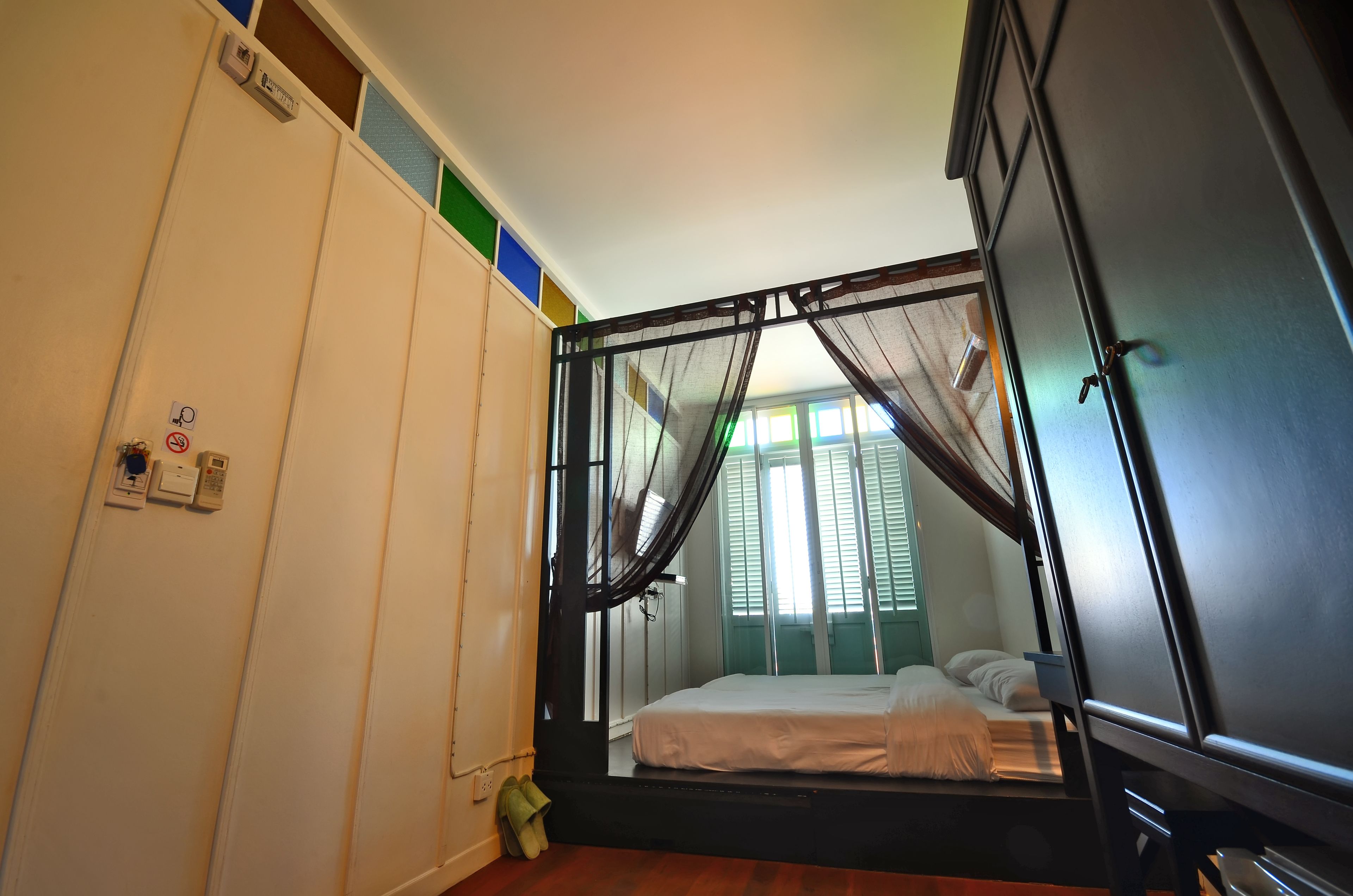 Un dormitorio con cama, armario y ventana con cortinas.
