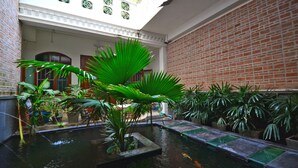 Een binnenplaats met een waterpartij, plantenpotten en een bakstenen muur.