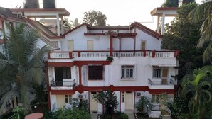 A multi-story building with balconies, air conditioning units, and a small garden area with benches and a water feature. - Atlanta Beach Resort (Calangute)