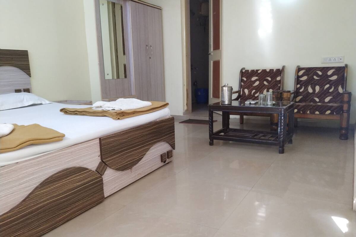 Una habitación de hotel con cama, armario, mesa y sillas, y un espejo.