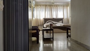 A hotel room with a bed, a desk, a chair, a coffee maker, and a window with curtains. - Atlanta Beach Resort (Calangute)
