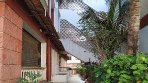 A narrow corridor with a tiled floor, bordered by red and white painted curbs, and lined with green plants and a palm tree. - Atlanta Beach Resort (Calangute)