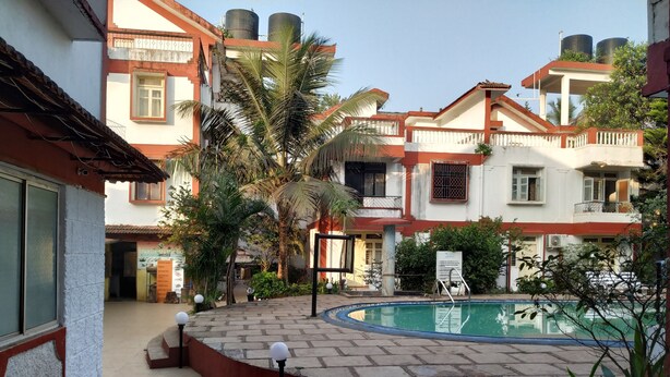 A courtyard with a swimming pool, steps leading to the pool, and a building with multiple balconies. - Atlanta Beach Resort (Calangute)
