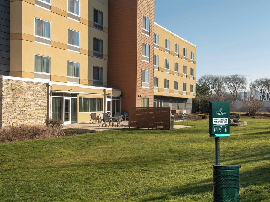 A multi-story hotel with a stone facade, a glass entrance, and a sign indicating pet-friendly policies.