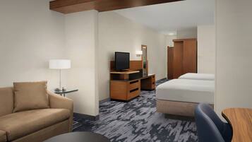 Een hotelkamer met een bank, een bed, een bureau, een televisie en een kledingkast.