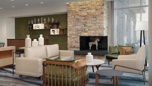 Un salon moderne doté d’une cheminée en pierre, de sièges confortables et offrant une vue sur l’extérieur.