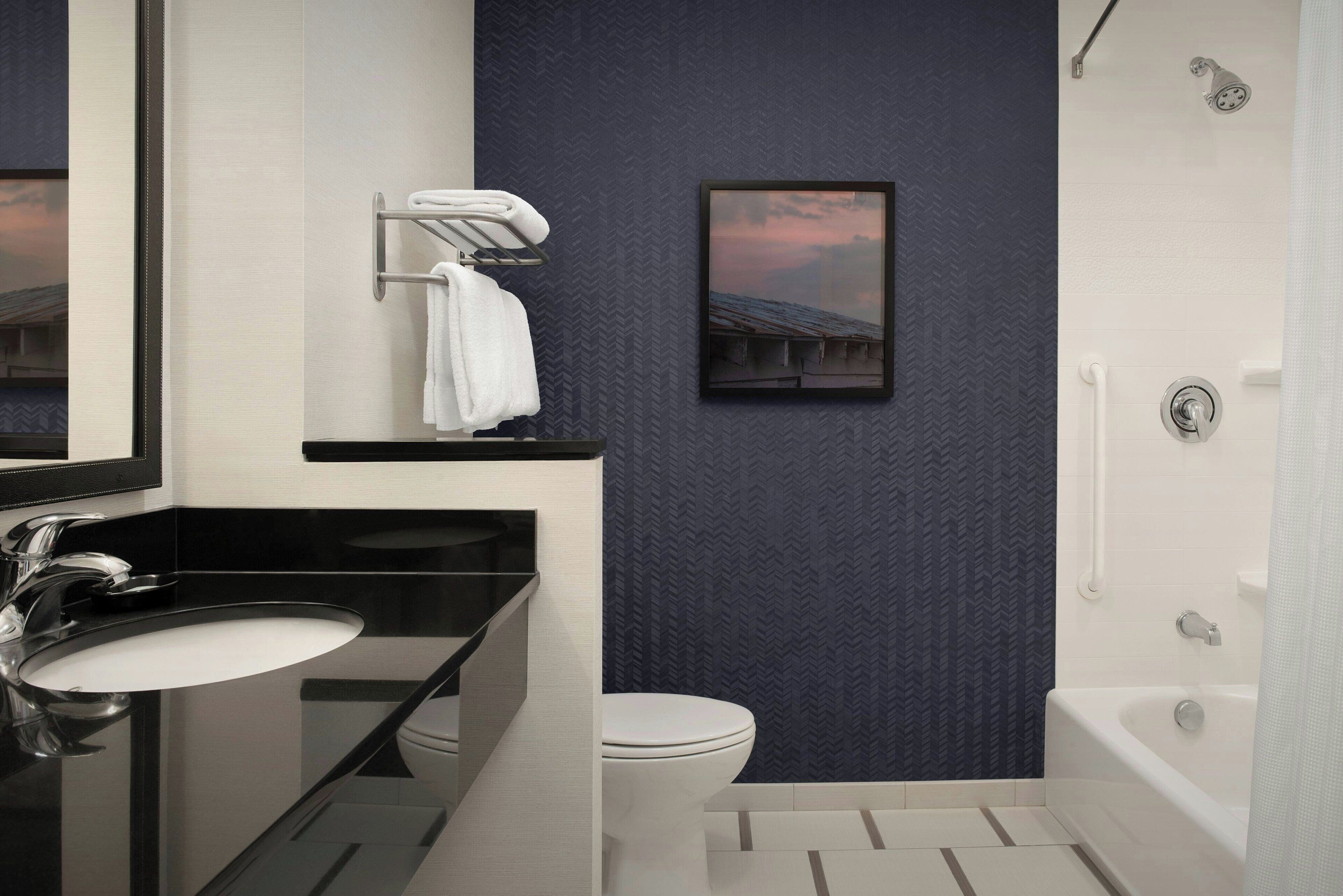 Een moderne badkamer met een zwart wastafel, een wit toilet en een bad.