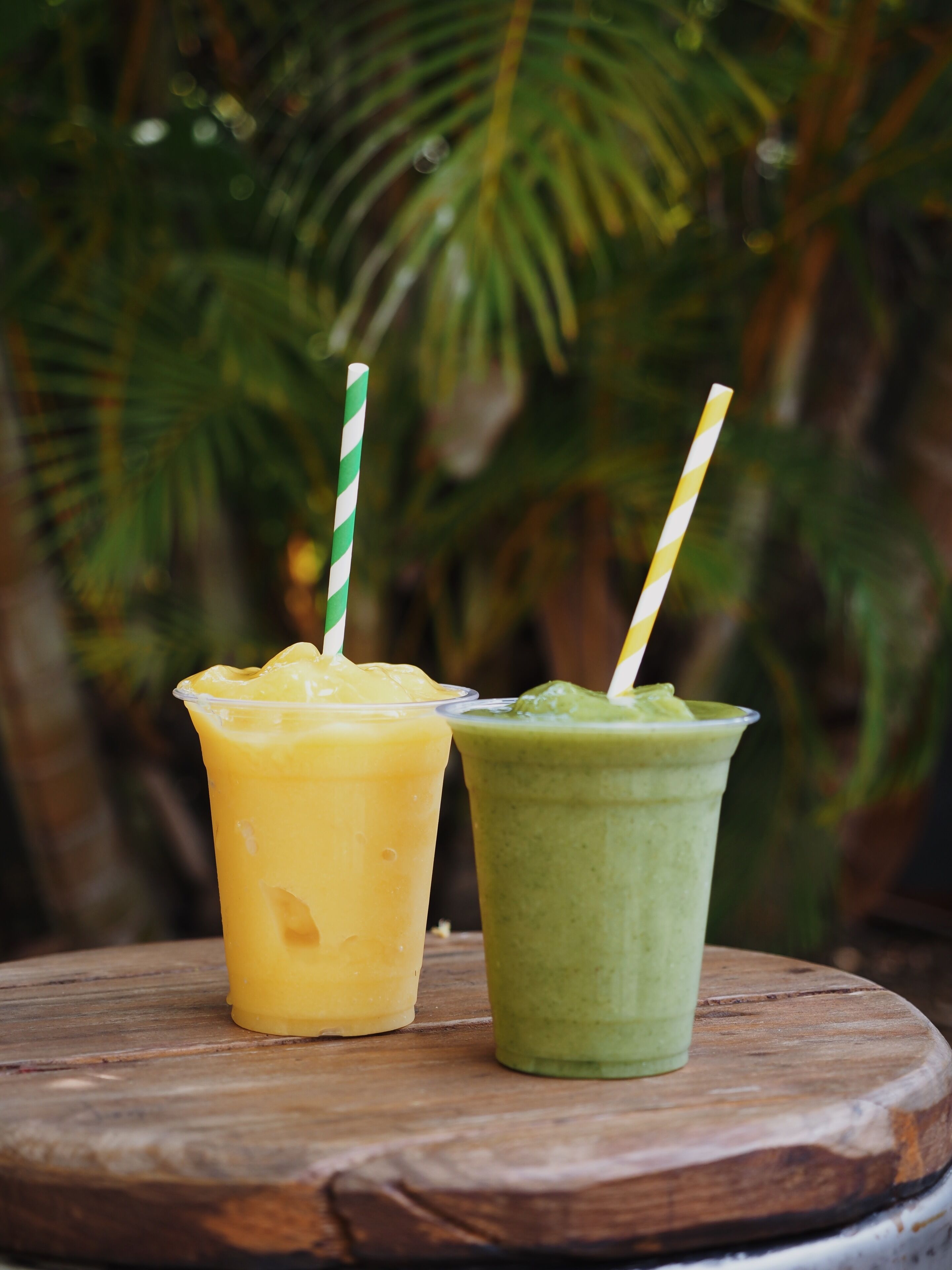 Two drinks on a wooden table with a blurred green background.