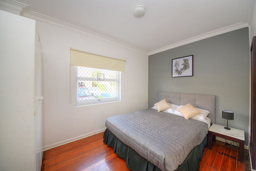 A bedroom with a bed, a nightstand, a window with a view, and a ceiling light.