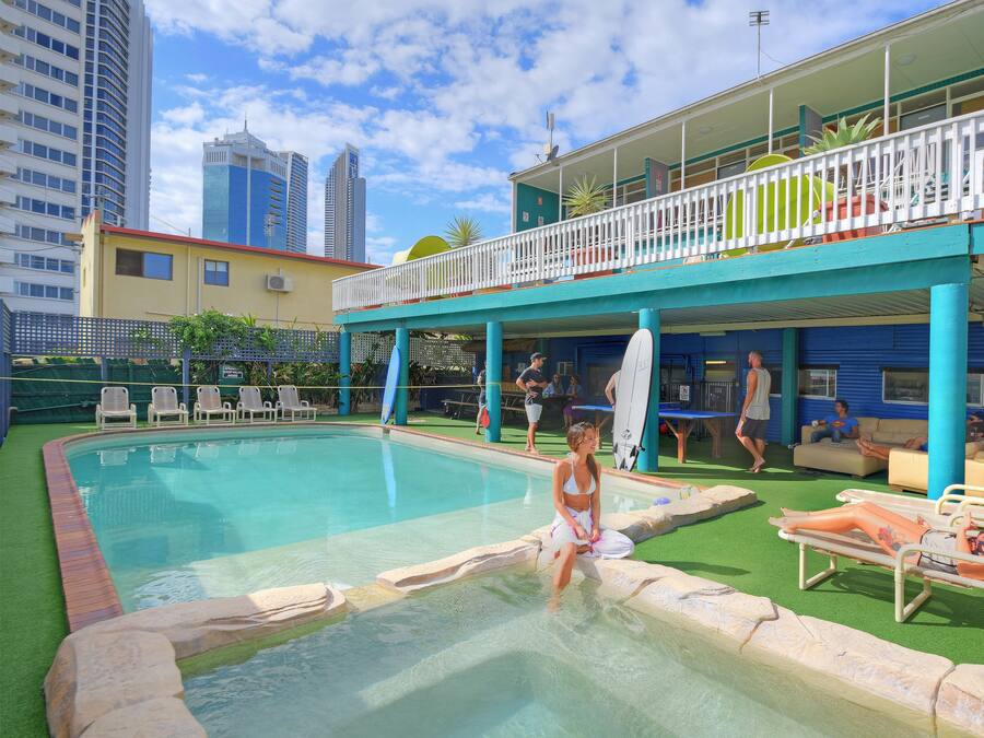 A pool area with lounge chairs and a building with a balcony.