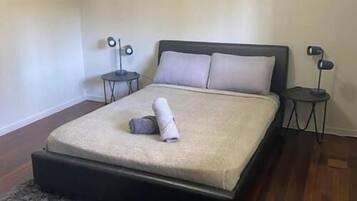 A bedroom with a bed, a rug, a painting, and two bedside tables.