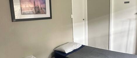Hotellihuone, jossa on kaksi erillistä sänkyä, kattotuuletin, seinällä oleva kehystetty taulu ja ovi, jossa lukee ”WC”.