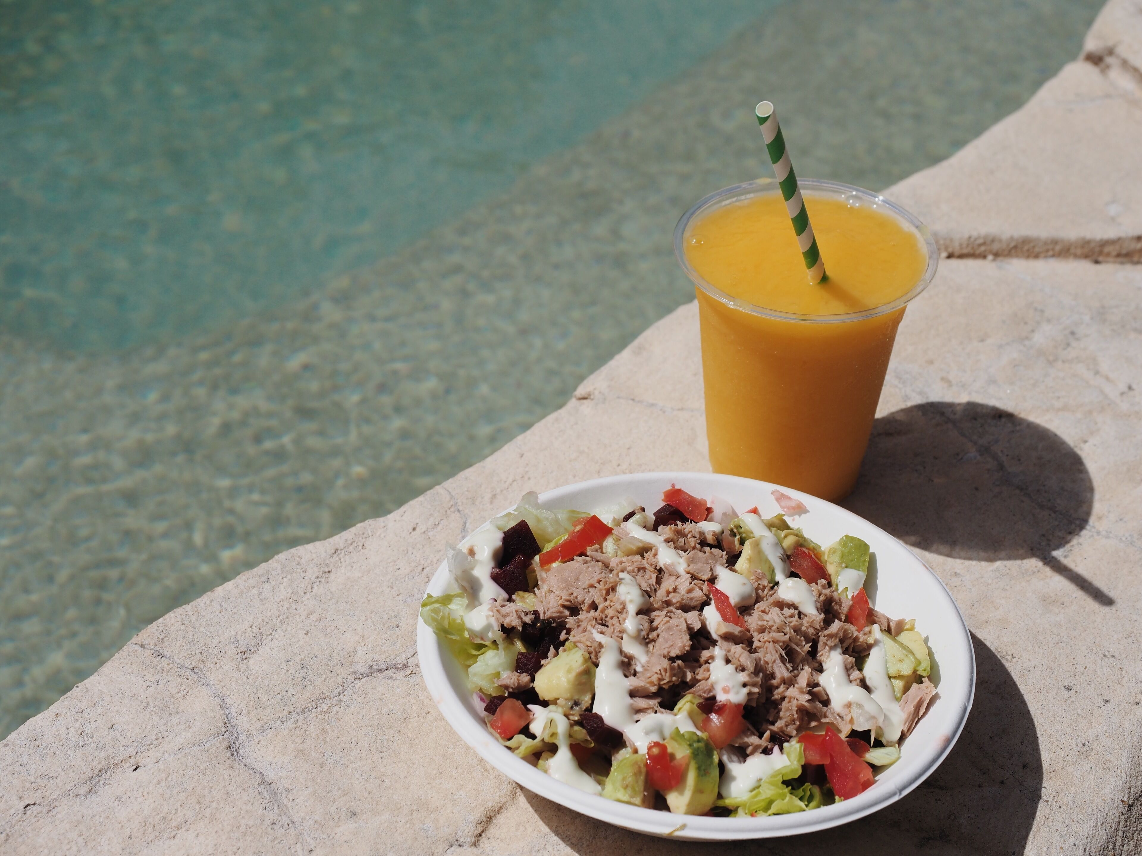 Ein Salat mit einem Getränk auf einer Steinfläche.