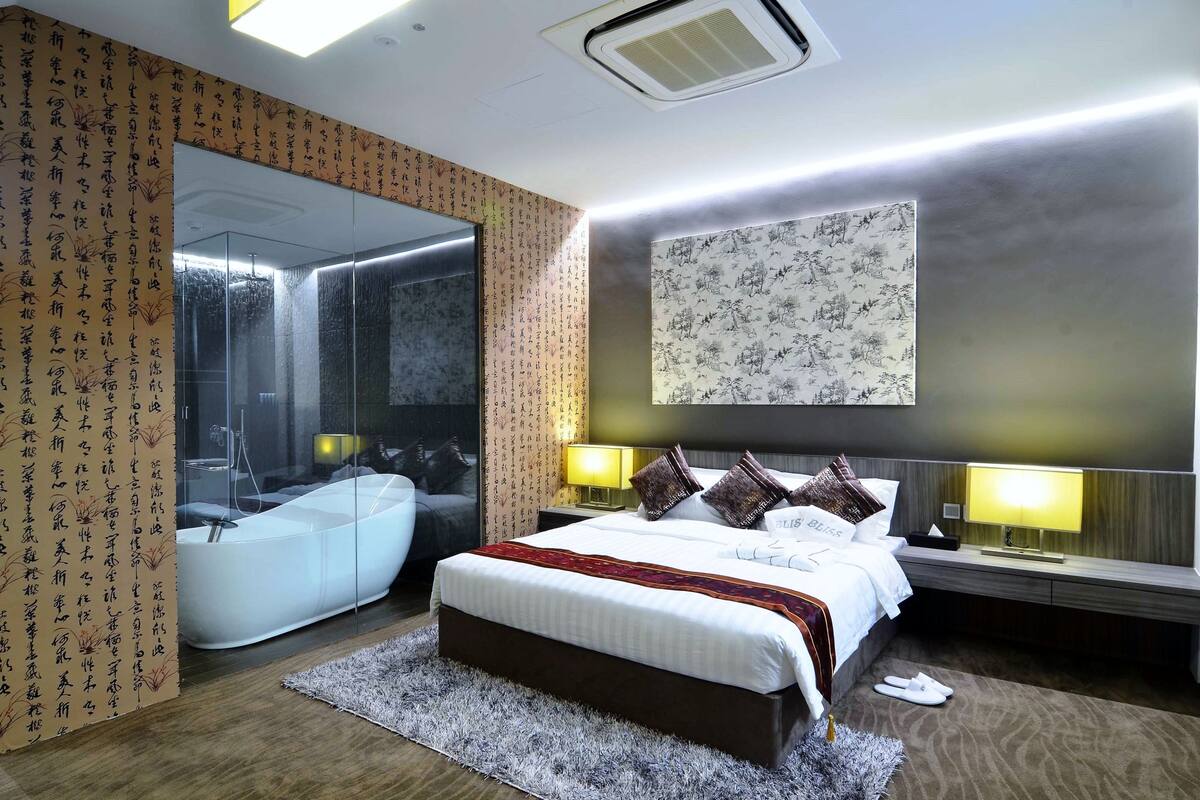 Une chambre d’hôtel moderne avec un grand lit, une baignoire et un grand miroir.