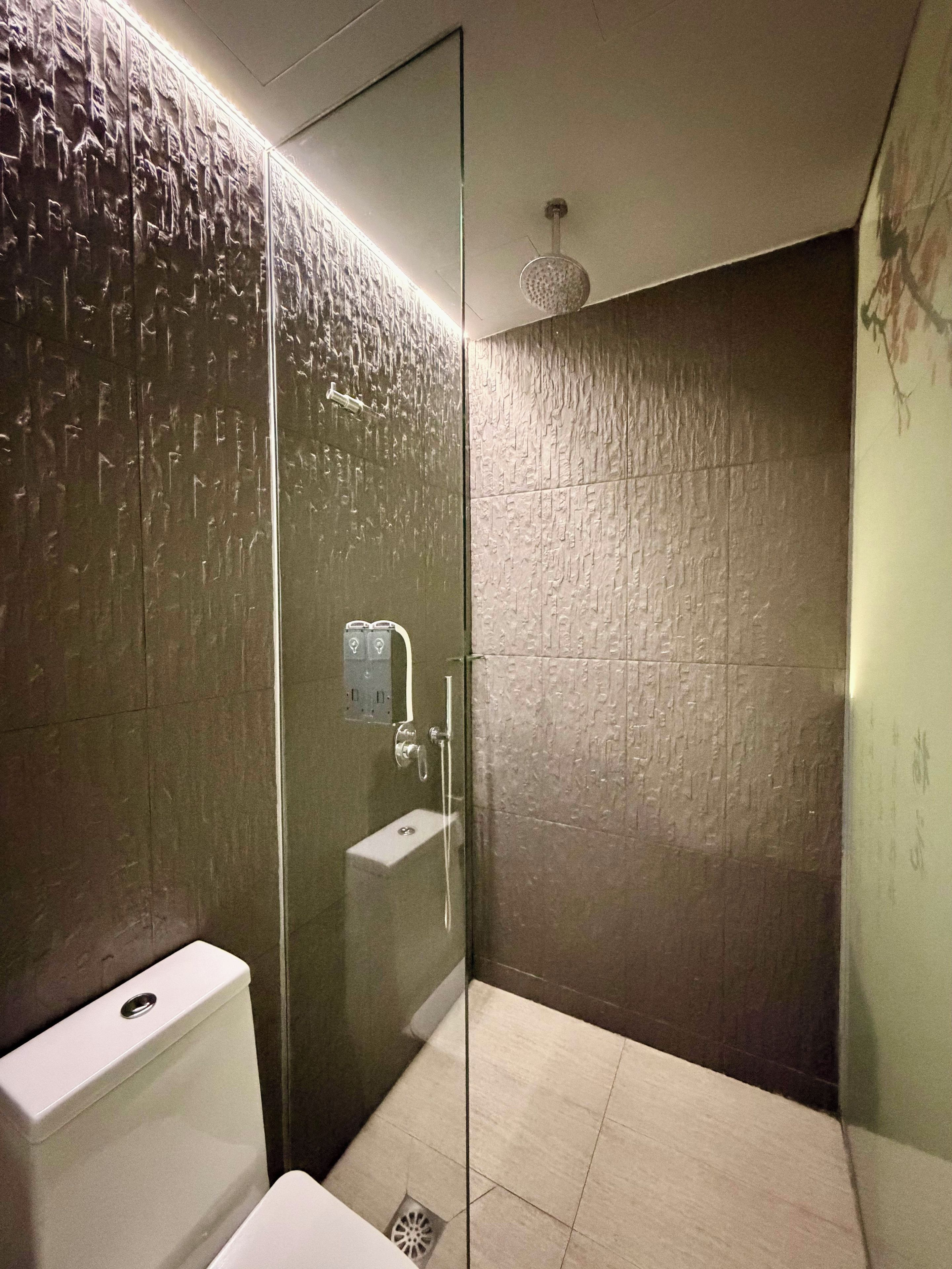 Ein modernes Badezimmer mit einer gläsernen Duschkabine, einer weißen Toilette und einem wandmontierten Waschbecken.