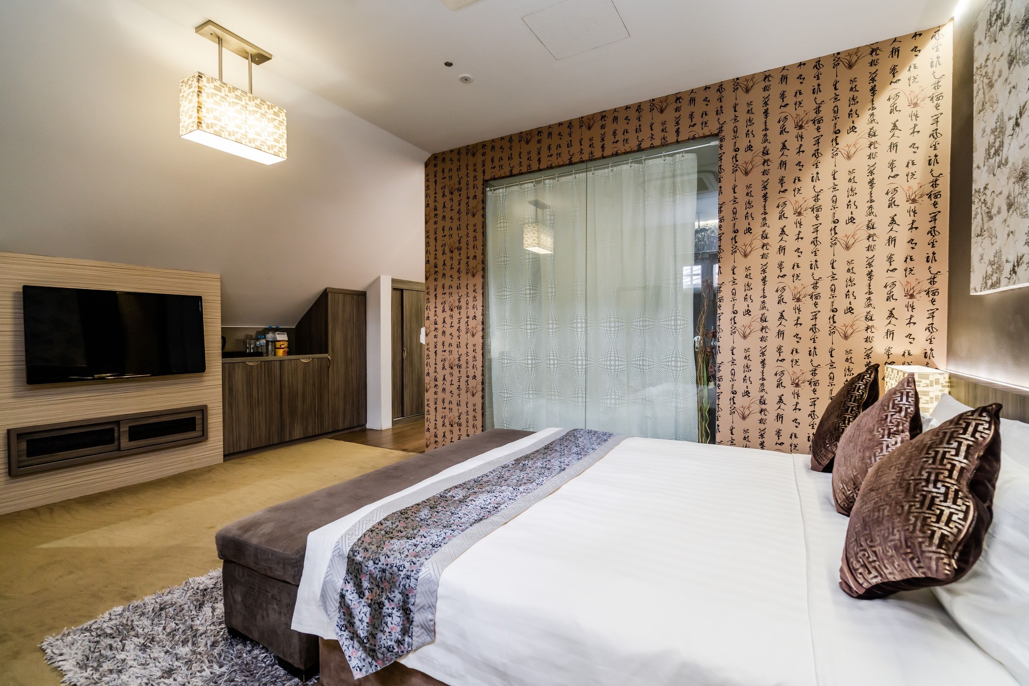 Una habitación de hotel moderna con una cama grande, televisión de pantalla plana, minibar y puerta corrediza de vidrio al balcón.