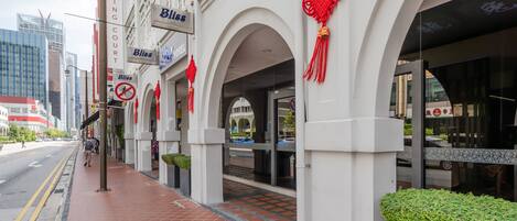 A hotel entrance with a red awning, a sign for 'Bliss Hotel', and a 'No Smoking' sign.