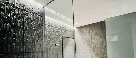 A modern bathroom with a glass shower enclosure, a white toilet, and a vanity with a mirror.
