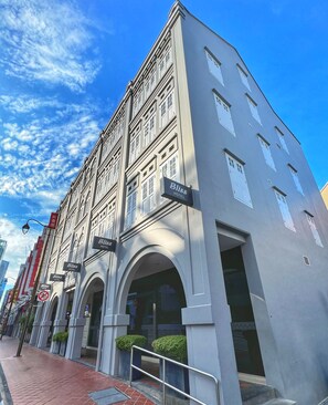 Un hotel con múltiples balcones, una entrada destacada con un arco y varios letreros que indican el nombre del hotel.