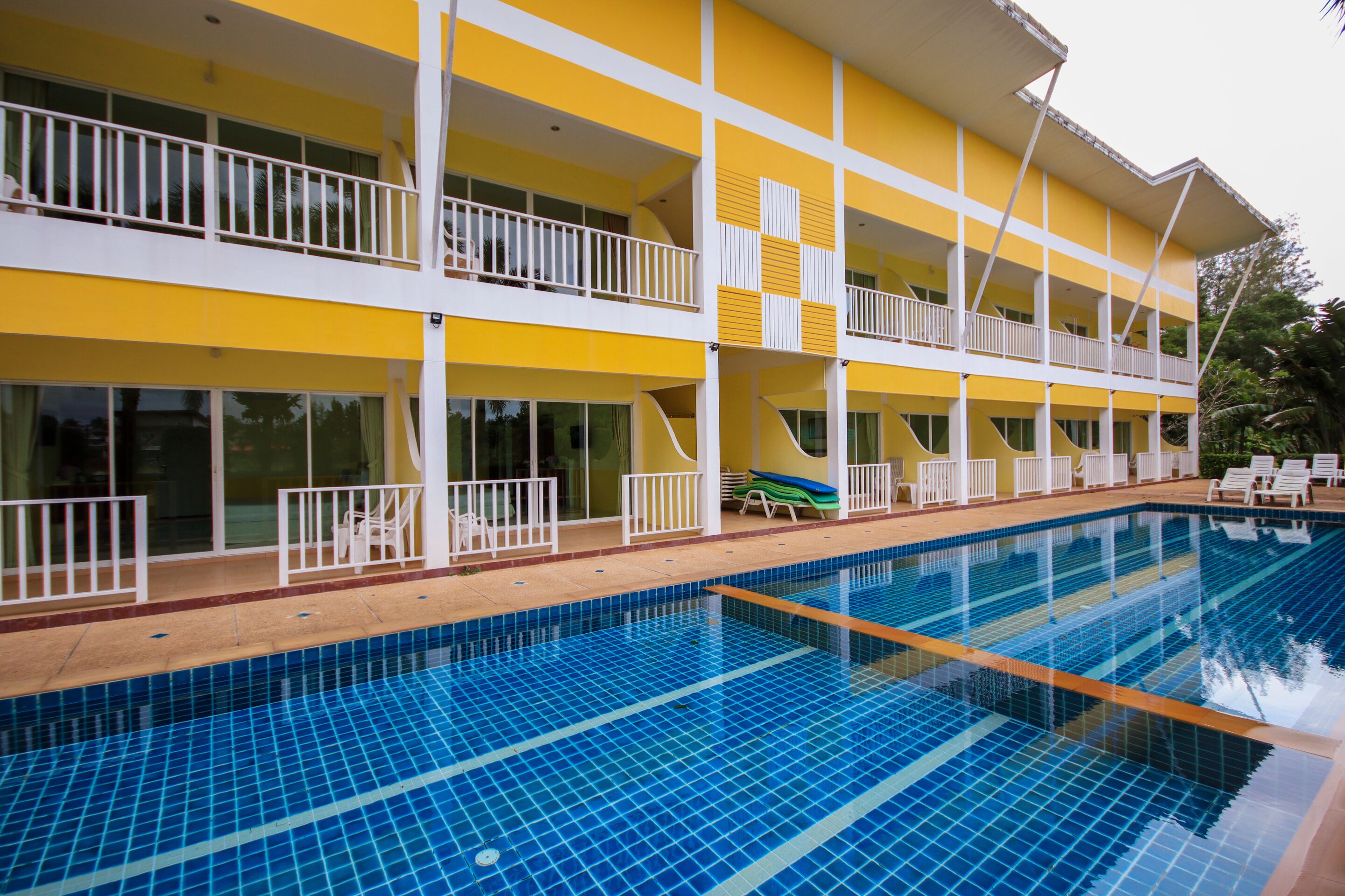 A hotel with a pool, balconies, and outdoor seating.