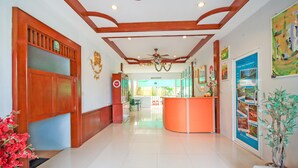 A hotel lobby with a reception desk, a restaurant sign, and a large painting on the wall. - Phuket Airport Sonwa Resort (Sa Khu)