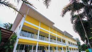 A multi-story hotel with balconies, a swimming pool, and palm trees. - Phuket Airport Sonwa Resort (Sa Khu)