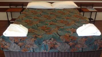 A bed with a floral bedspread, two pillows, and two towels on the bed.