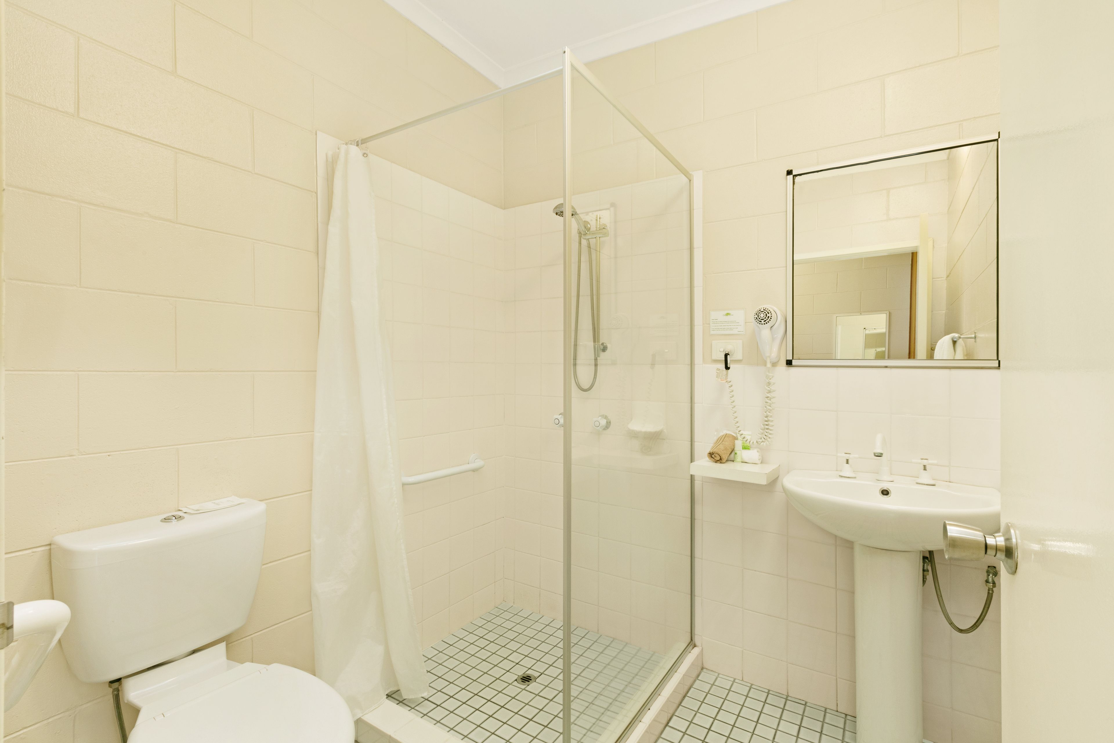 Une salle de bain avec une douche à parois de verre, des toilettes et un lavabo avec un miroir.
