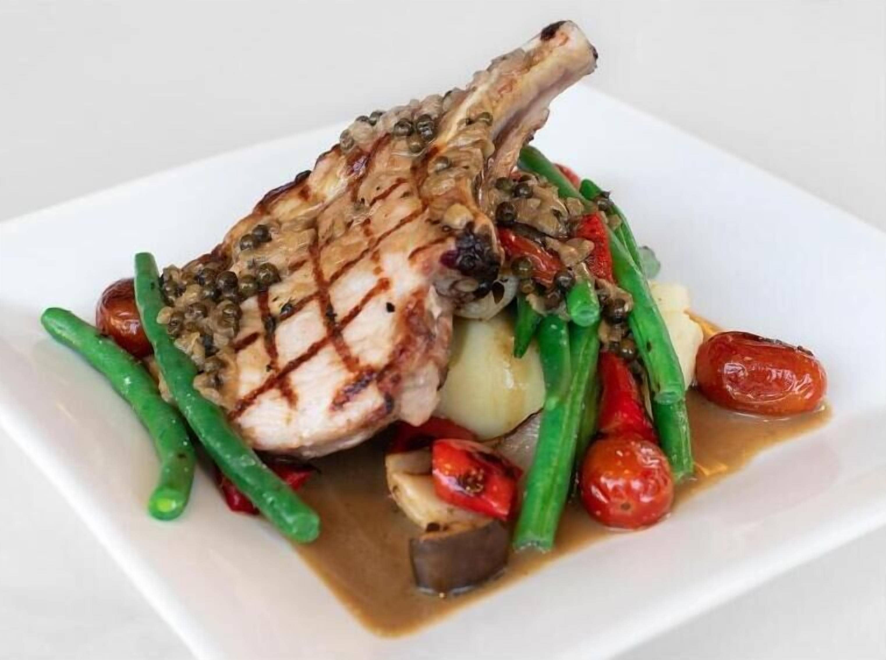 A plate of grilled meat with vegetables and sauce.
